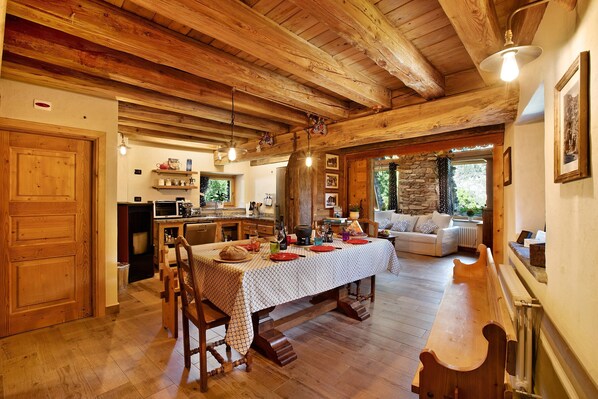Un interior rústico de madera con una mesa de comedor, sillas, una zona de cocina y un rincón de estar acogedor.