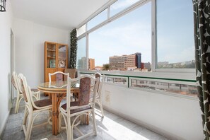 Un balcon avec une table et des chaises pour prendre les repas, une vitrine et une vue sur des bâtiments situés de l’autre côté d’une étendue d’eau.
