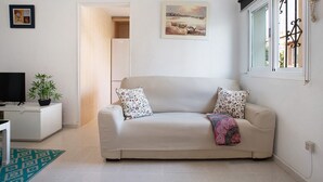 A living room with a sofa, a TV, a plant, and a painting on the wall. - Apartment 'Prealsa Benalmádena' with Sea View, Shared Pool and Private Terrace (Benalmádena)