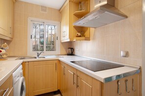 A kitchen with wooden cabinets, a built-in oven, a window, and a sink.