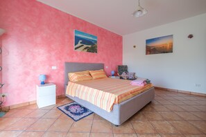 Une chambre à coucher comprenant un lit, une table de chevet, une lampe et deux tableaux accrochés au mur.