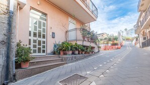 A building with a stone facade, a metal staircase, and potted plants. - Apartment 'Meizon Sicilia' with Balcony, Wi-Fi and Air Conditioning (terme vigliatore)