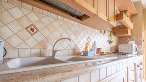 A kitchen with two sinks, a microwave, and wooden cabinets. - Apartment 'Meizon Sicilia' with Balcony, Wi-Fi and Air Conditioning (terme vigliatore)