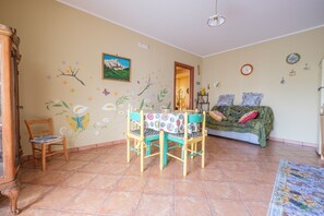 Un espace repas comprenant une table et des chaises, un canapé et un mur agrémenté d’éléments décoratifs.