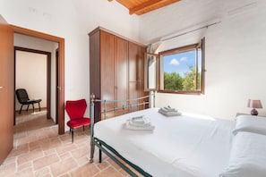 Un dormitorio con cama, una silla roja, un armario y una ventana con vistas.