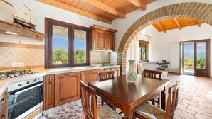 A kitchen with wooden cabinets, a dining table, and a view through an archway.