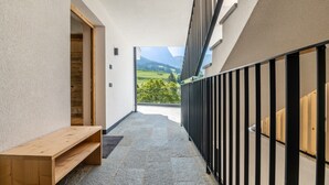 A corridor with a wooden bench, a view of a green landscape, and a balcony with a black railing. - Holiday Apartment "Chalet Kasch Glück" with Mountain View, Private Terrace & Wi-Fi (Fiè allo Sciliar)