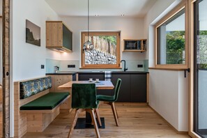 Una cocina compacta con comedor, banco de madera y vistas por la ventana.