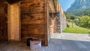 Una cabaña de madera con fachada de piedra, una escalera de piedra y vistas a la montaña.
