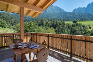 Une terrasse en bois avec une table dressée pour le petit-déjeuner, offrant une vue sur un paysage montagneux.