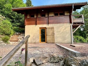 A wooden cabin with a single door, a small porch, and a staircase leading to a deck. - Chalet "Entierement Rénové au Calme" with Mountain View, Private Terrace & Wi-Fi (Le Tholy)