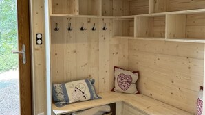 Un intérieur en bois avec un banc, des crochets et un panier.