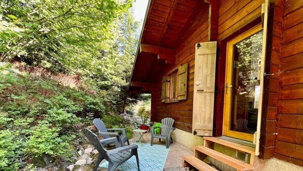 Une cabane en bois dotée d’un patio aménagé avec du mobilier d’extérieur et une petite table.