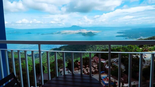 Un balcon offrant une vue sur un paysage côtier, comprenant une montagne et la mer.