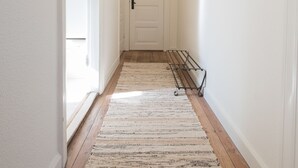 A hallway with a wooden floor, a white door, and a wall-mounted rack. - Spacious 2-Bed Apartment in Aalborg (Aalborg)