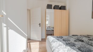 A bedroom with a bed, a wardrobe, and a door leading to another room. - Spacious 2-Bed Apartment in Aalborg (Aalborg)