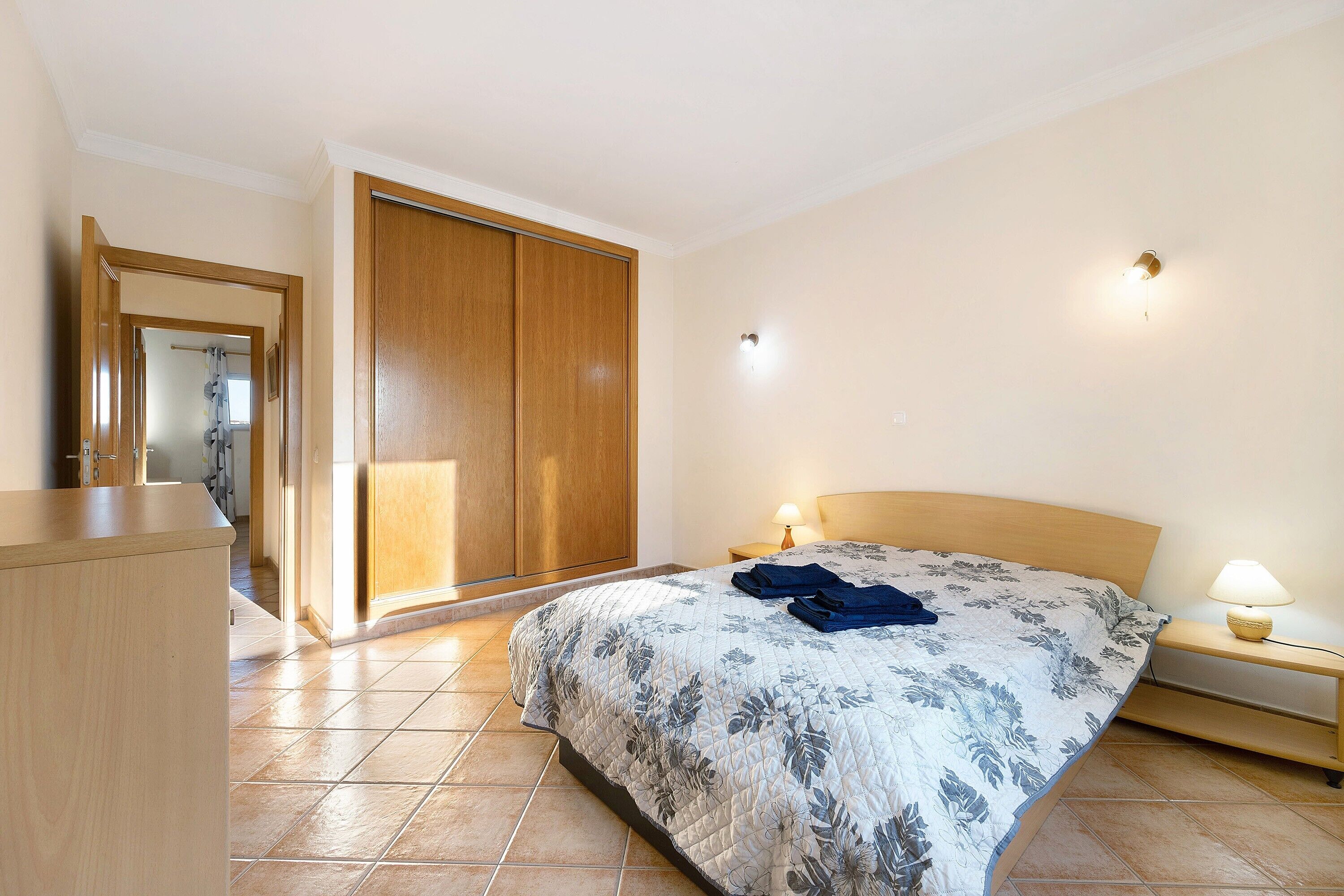 A bedroom with a bed, bedside tables, a wardrobe, and a mirror.