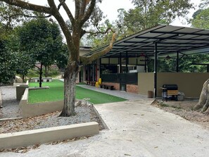 A covered outdoor area with a barbecue grill, seating, and a grassy lawn. - Private Pool FamilyResort Bentong Pahang (Raub)
