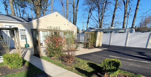 A residential property with a garage, a small garden with flowering plants, and a white fence.