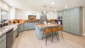 A modern kitchen with a central island, bar stools, and stainless steel appliances. - 4,500 sq-ft retreat with a pool and hot tub in the middle of wine country!  (Templeton)