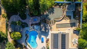 An aerial view of a residential property with a swimming pool, solar panels, and a well-maintained garden. - 4,500 sq-ft retreat with a pool and hot tub in the middle of wine country!  (Templeton)