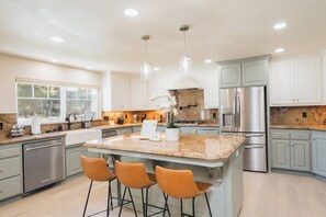 A modern kitchen with a central island, stainless steel appliances, and pendant lighting. - 4,500 sq-ft retreat with a pool and hot tub in the middle of wine country!  (Templeton)