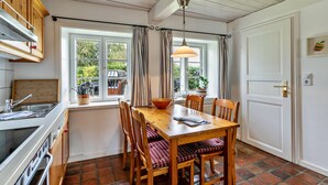 Una cocina con una mesa de madera, sillas y una ventana con cortinas.