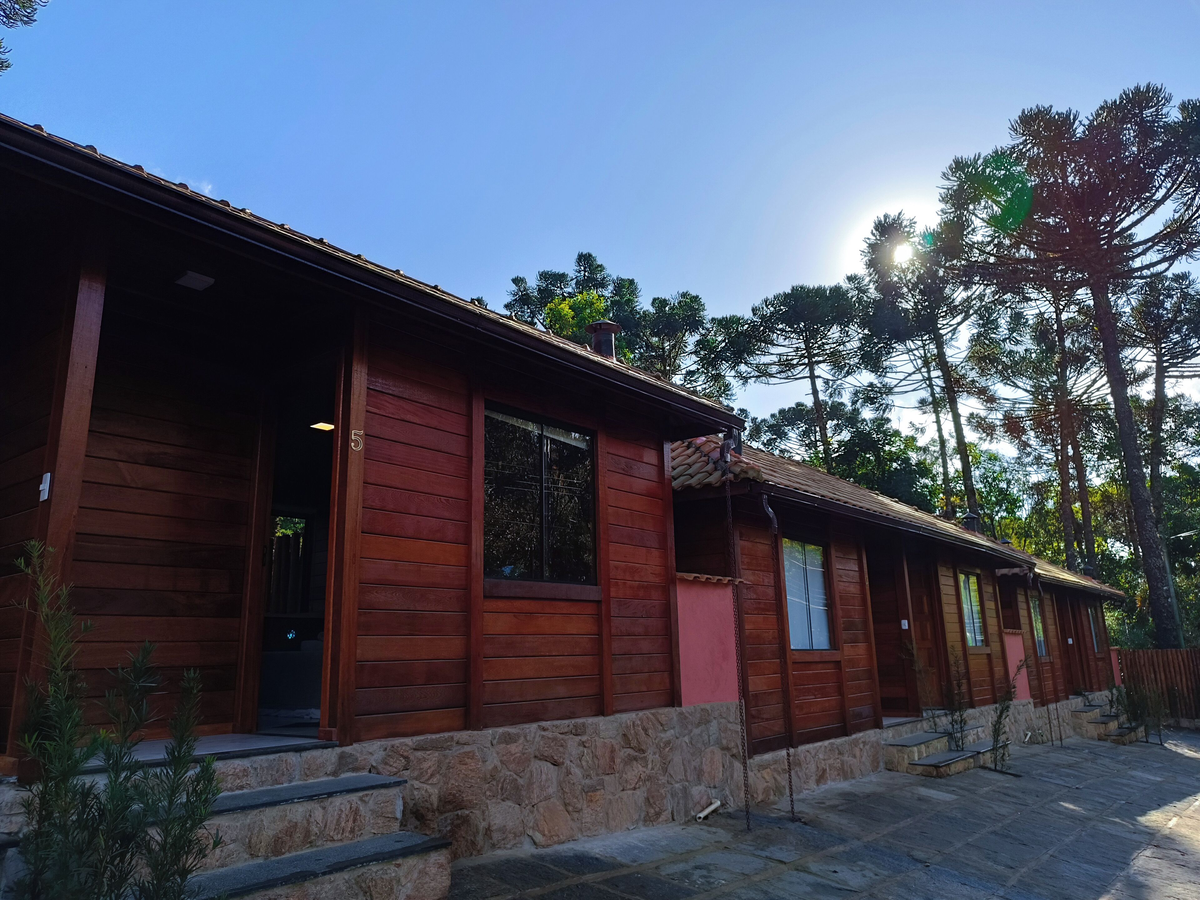 A wooden cabin with a stone foundation, large windows, and a porch.