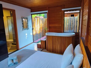 Une chambre à coucher avec un lit, une tête de lit en bois, un lavabo intégré et une vue sur l’extérieur.