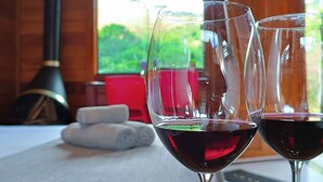 Dos copas de vino sobre una mesa de madera con vistas a la vegetación a través de una ventana.