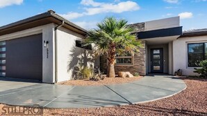 A modern two-story house with a garage, a palm tree, and a landscaped driveway. - Ivins Oasis : Private Hot Tub & Pool (Ivins)