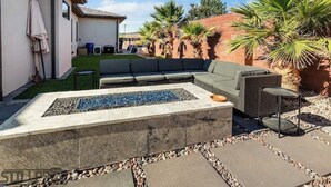 A patio with a fire pit, outdoor furniture, and palm trees. - Ivins Oasis : Private Hot Tub & Pool (Ivins)