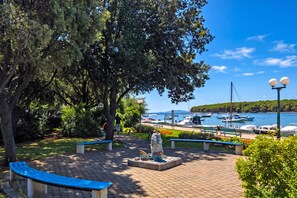 Ein Park mit Bänken, einer Statue und Blick auf Boote auf dem Wasser.