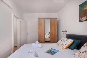 A hotel room with a bed, a wardrobe, a painting, and a magazine on the bed. - Seafront Apartment Nana 2, Punat, Croatia (Punat)
