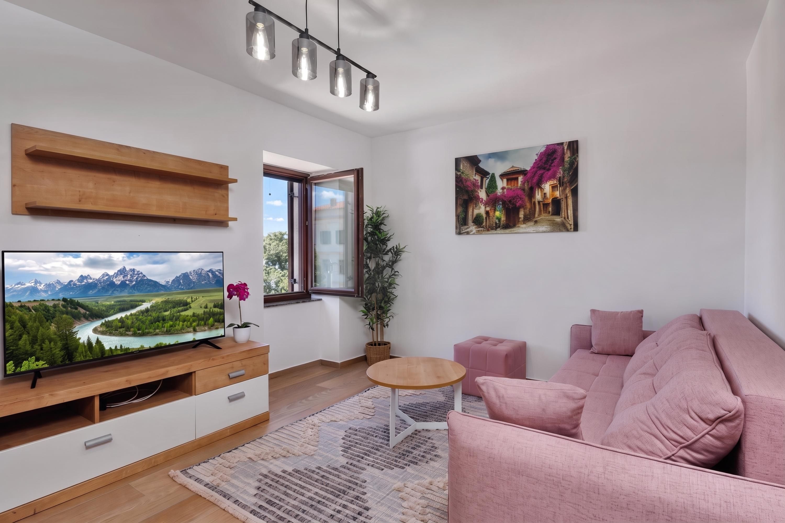 A modern living room with a flat-screen TV, wooden shelves, a pink sofa, a small round table, and a painting of a street scene.