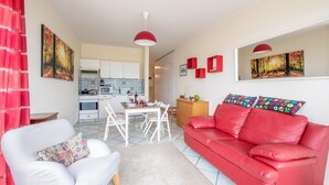 A modern living room with a red leather sofa, a white armchair, and a dining area with a table and chairs. - Pazzallo Panoramica with Balcony and Garage, Lugano, Switzerland (Lugano)