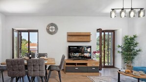 Un salon moderne comprenant un coin repas, un téléviseur à écran plat et une grande fenêtre.