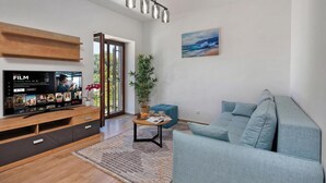 Un salon moderne avec un téléviseur à écran plat, un canapé bleu, une table basse et une plante en pot.