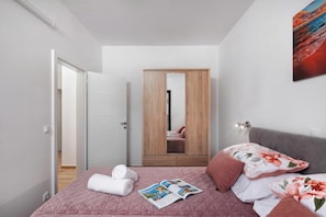 A modern bedroom with a bed, a wooden wardrobe, and a large mirror. - Seafront Apartment Nana 1, Punat, Croatia (Punat)