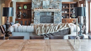 Amplia sala de estar con chimenea de piedra, vigas de madera y un candelabro.