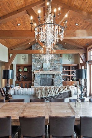A spacious living area with a stone fireplace, wooden beams, and a chandelier. - Alpine Sanctuary | Deer Valley | Private Hot Tub (Park City)