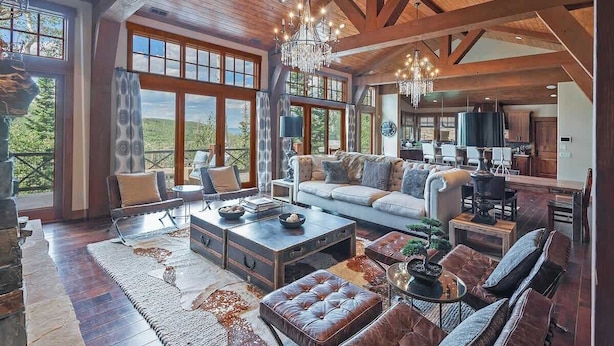 Un amplio salón con chimenea, ventanas grandes y un techo alto con vigas a la vista.