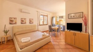 Una habitación de hotel con cama, escritorio, televisión y obras de arte en las paredes.