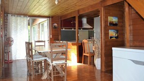 L’intérieur d’un chalet en bois comprend un coin repas, une cuisine et offre une vue sur l’extérieur.
