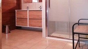 Une pièce avec un mur en bois, une porte-fenêtre coulissante, un cadre de lit en métal et un sol carrelé.