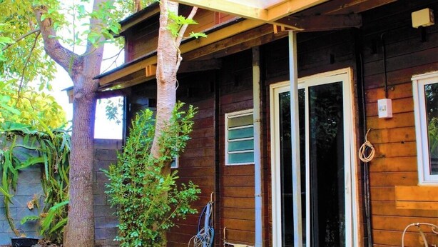 Une maison en bois avec une porte en verre, un jacuzzi et un arbre dans le jardin.