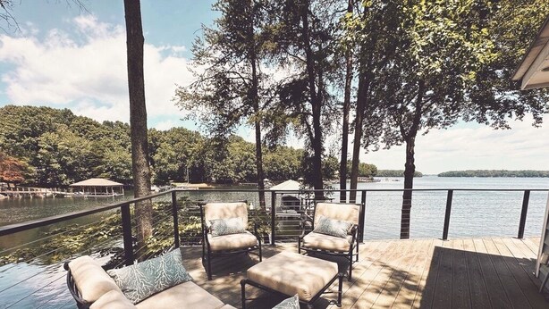 Una terraza con asientos al aire libre, con vista a un lago y un área boscosa.