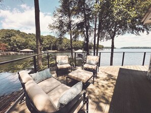 A deck with outdoor seating, overlooking a lake and forested area. - Loft at LKN- Private Dock, Hot Tub, Fire Pit (Huntersville)
