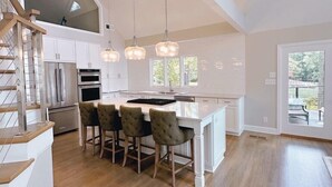 Una cocina amplia con una isla central, suelo de madera e iluminación colgante.