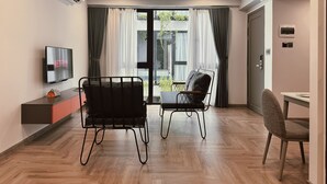 A modern living room with a flat-screen TV, two chairs, a small table, and a sofa. - TUK TAK SPACES (Da Nang)